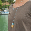 Sautoir doré et bleu ciel, pendentif en forme de coquillage doré. Fabrication française et artisanale.