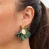 Les boucles d'oreilles Dounia : des boucles d'oreilles en tissu en forme de fleur vertes. Elles sont également constituées de pendentif rond en métal doré d'un flash d'or 24 carats et d'un anneau ovale en métal doré d'un flash d'or 24 carats.