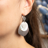 Les boucles d'oreilles Viviane se composent d'un pendentif rond en nacre blanc, d'un pendentif oval et rond en métal plaqué argent 999. Elles sont fabriquées et conçues en  France sur la côte Ouest.