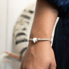 Le bracelet Cinéma est un bijou artisanal composé d'un cordon en lin beige et d'un pendentif en forme d'étoile en céramique façonné à la main.