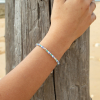 Le bracelet Marinière : un bracelet fin et lumineux composé de perles en verre blanches, de perles en verre émeraude, de perles en métal plaqué argent 999 et de perles rayées bleu marine et blanc.