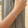 Le bracelet Marinière : un bracelet fin et lumineux composé de perles en verre blanches, de perles en verre émeraude, de perles en métal plaqué argent 999 et de perles rayées bleu marine et blanc.