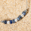 Forio est un bracelet composé d'un câble en métal plaqué argent 999 sur lequel est disposé des perles bleu gris. Une création Retour de plage.