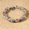 Pétale est composé de perles en verre grises et roses et de rondelles en métal plaqué argent 999.