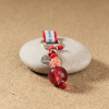 Porte-clefs composé d'une perle en verre rose, d'une perle orangé, d'une perle de rocaille rouge et d'un cordon en coton rouge.