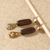 Détail des boucles d'oreilles Neko avec pendentif rectangulaire en bois naturel foncé et goutte dorée texturée, création artisanale française