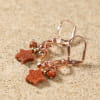 Détail des boucles d'oreilles Samedi avec étoile et perle en pierre de sable marron sur monture en métal doré rose – création artisanale française élégante