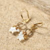 Boucles d'oreilles Vega Retour de Plage en métal doré à l'or fin 24 carats, ornées de pendentifs en forme d'étoile et de perles en nacre blanche, montées sur fines dormeuses dorées – bijou artisanal fabriqué en France