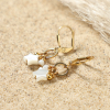 Détail des boucles d'oreilles Vega avec pendentifs en étoile et perles en nacre blanche, fermoir dormeuse doré – création artisanale française