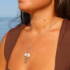 collier Grigri argenté avec pendentif multicharme porté sur décolleté plongeant