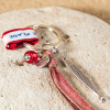 Porte-clefs Nicoise : un porte-clefs coloré composé d'un poisson en métal plaqué argent 999, d'un ruban tissé en coton rouge, d'une perle en verre recyclé rouge et d'un ruban en coton rouge Retour de plage.