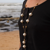 Micheline est un sautoir de 49 cm composé de perles en céramique beige, de perles rondes en métal doré par un flash d'or 24 carats et d'un cordon en fil écru.