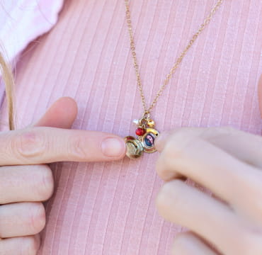 Zoom sur le collier Oma rouge et doré, sur fond rose – création française