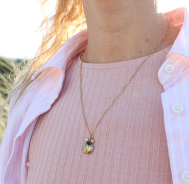 Collier Oma doré au pendentif bleu, zoomé sur fond rose – fabrication française