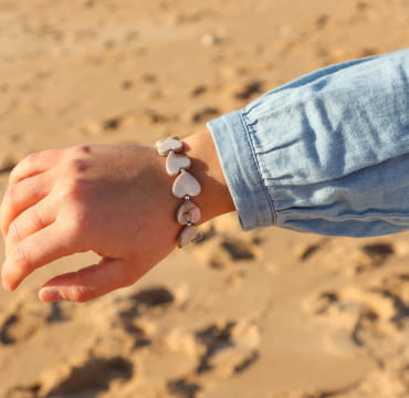 Gros plan sur le bracelet Love argenté et gris porté avec une chemise en jean – création française