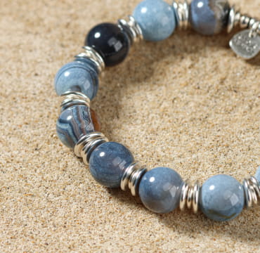 Zoom sur le bracelet Minke bleu profond, bijou artisanal posé sur le sable