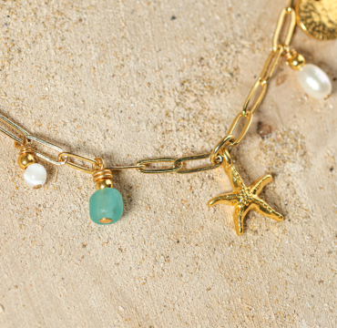 collier Dolcevita doré avec pendentifs vert d’eau sur sable clair