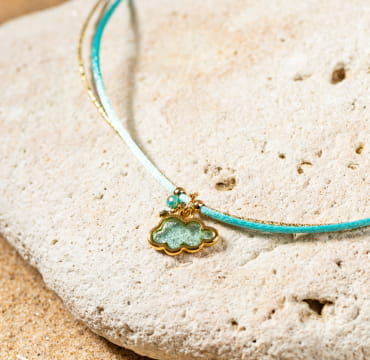 Mochi est un collier pour enfant turquoise composé d'un pendentif en forme de nuage à paillettes et d'un cordon en coton turquoise.