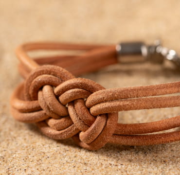 Le bracelet Homère : un bracelet pour homme composé de cordons en cuir beige. Agrémenté d'un délicat noeud marin, il incarne parfaitement l'élégance et le style.