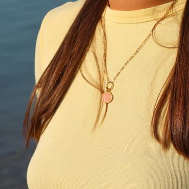 collier Caliopee doré avec pendentif corail porté sur haut clair