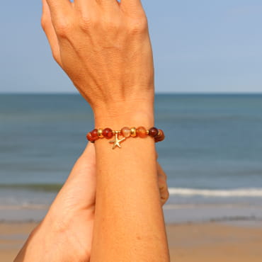 Bracelet Culcita doré à l’or fin et perles terracotta, création française inspirée des rivages ensoleillés.