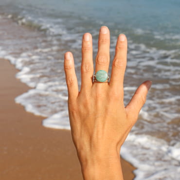 bague Oléronaise argentée avec pierre vert d’eau, portée face à l’océan, fabrication française