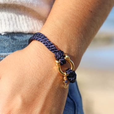 bracelet Manille doré avec corde bleu marine porté à la main gauche