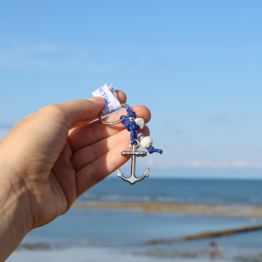 porte-clés Gamme argenté avec cordelette bleu marine et ancre en métal tenu à la main