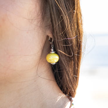 boucle d’oreille Seiche portée, perle jaune solaire suspendue à une monture argentée