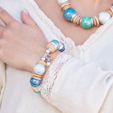 Bracelet Coco bleu ciel au poignet, détails en perles nacrées et monture argentée, finition estivale élégante.