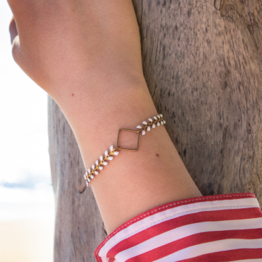 bracelet Troène en métal bronze et perles blanches, posé sur le sable