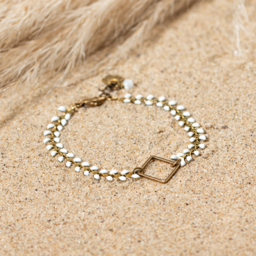 bracelet Troène en métal bronze et perles blanches, posé sur le sable. Fabrication française