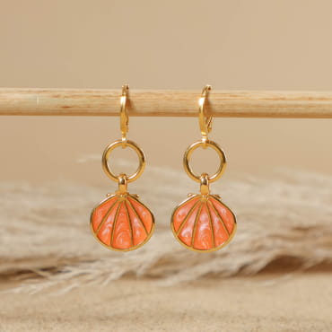 boucles d’oreilles Caliope doré avec perles corail posées sur fond sable