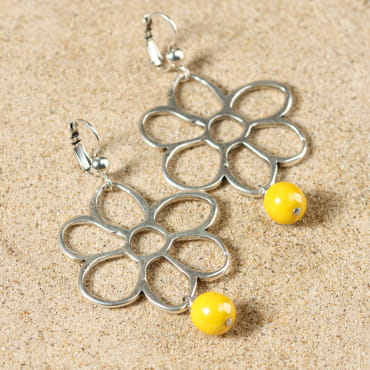 Boucles Janis en métal argenté, tressage artisanal et perles jaune vif sur fond sable.