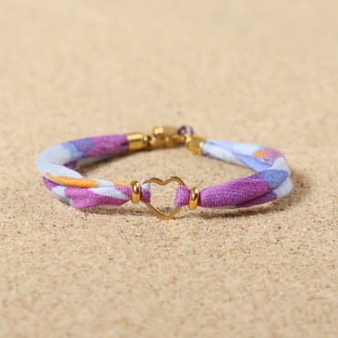 bracelet Maman doré avec cordon violet et perles décoratives sur sable clair