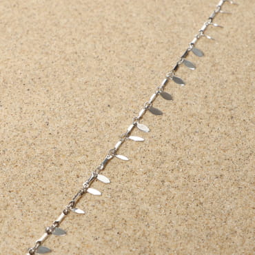 bracelet de cheville Feuillage argenté avec maillons feuillus posé sur tissu clair