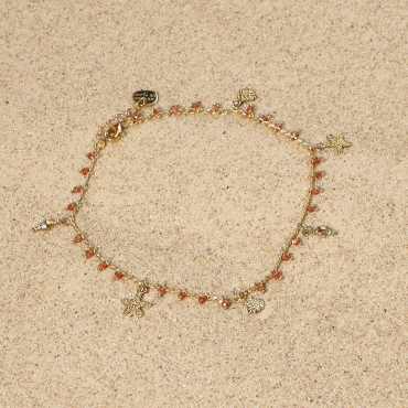 bracelet de cheville Ponta doré avec perles terracotta posé sur tissu clair