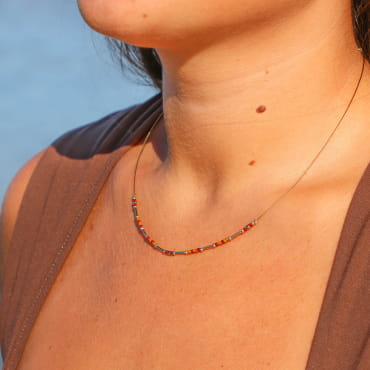 collier Huari doré avec perles rouges porté sur buste avec haut orange