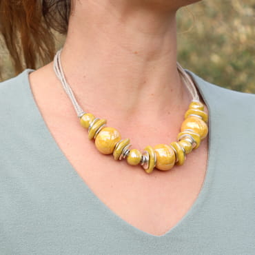 Collier en métal argenté aux perles jaunes lumineuses, mis en valeur sur un haut échancré.