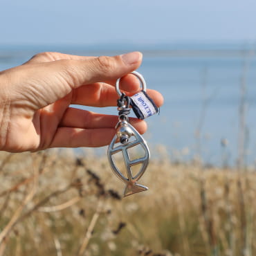 porte-clés Merlan argenté et bleu marine tenu en main