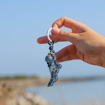 porte-clés Oléron argenté orné de corde bleue marine tenu en main