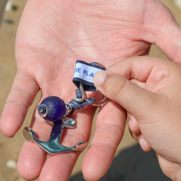 Porte-clés Thonon artisanal en métal argenté et corde bleu marine à rayures multicolores.