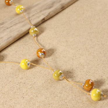 Détail du sautoir Crème avec perles en céramique jaune et médaille Retour de Plage – création artisanale française