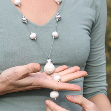 Sautoir Patèl blanc et argenté porté sur un pull gris – bijou long élégant