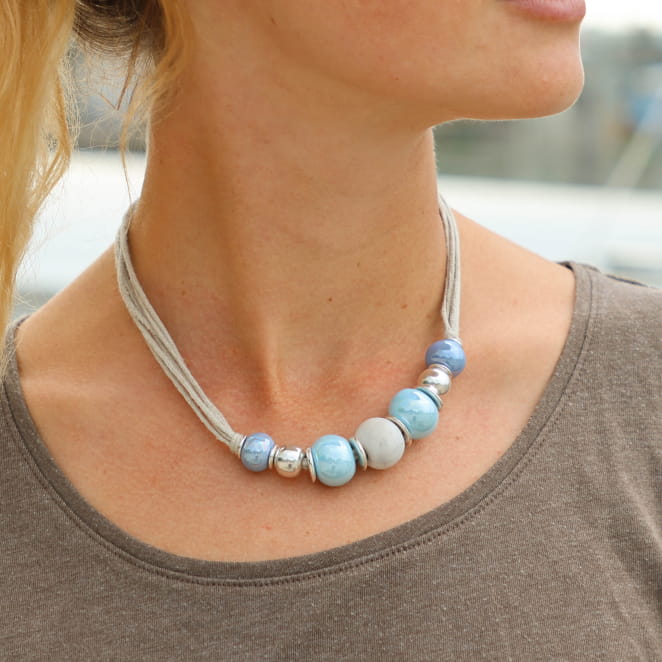 Collier avec un camaieu de bleus et de perles en céramique, autour d'un cordon en lin. origine France Garantie.