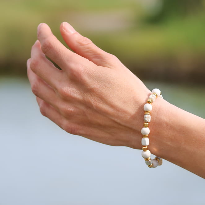 Bracelet artisanal en métal doré avec cordon blanc cassé, style élégant. Fabriqué en France.