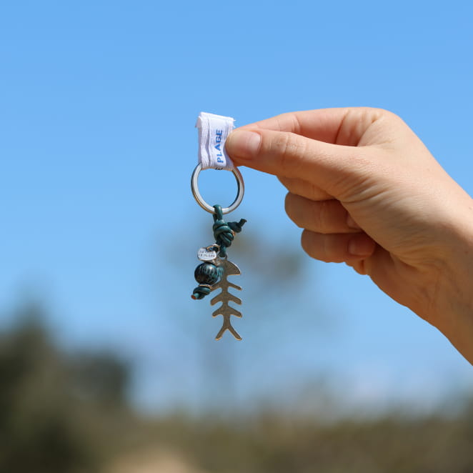 Porte-clés en métal argenté, corde bleu pétrole et perles décoratives. Création artisanale made in France.
