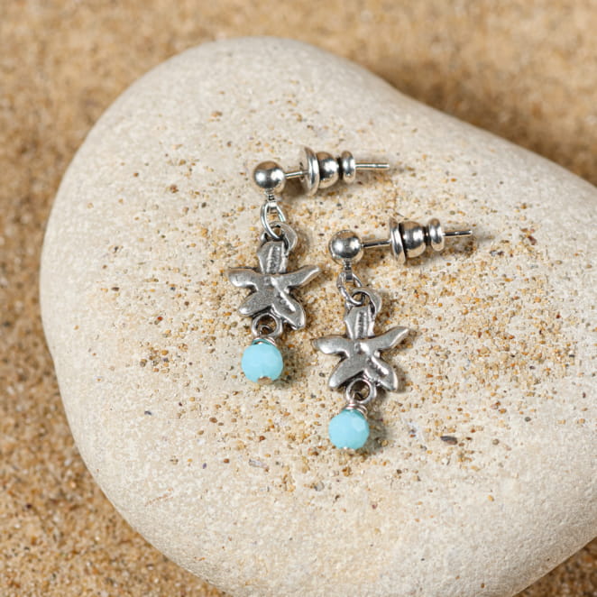 Boucles d’oreilles enfant Ibiza bleu ciel, posées sur sable – bijou argenté fait main