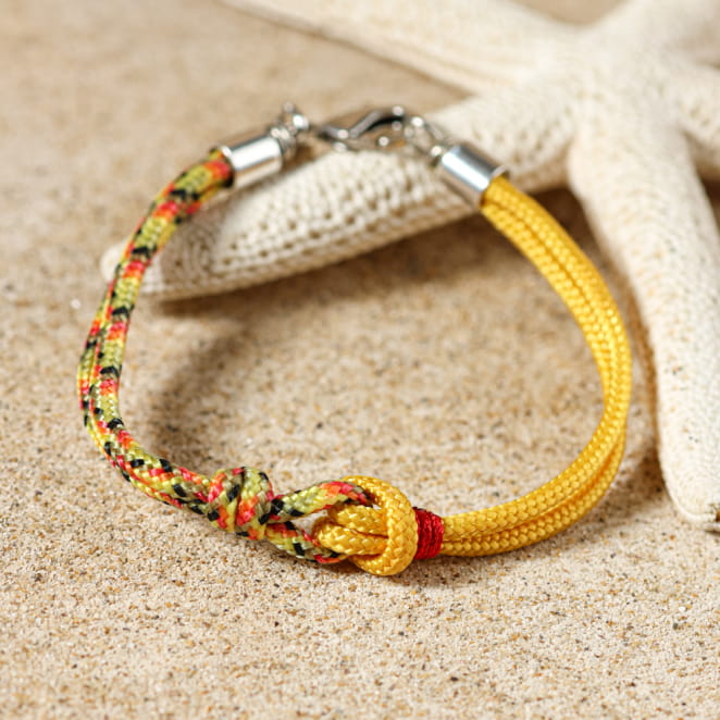 Bracelet Dinan jaune et argent pour enfant, posé sur le sable – fabrication française