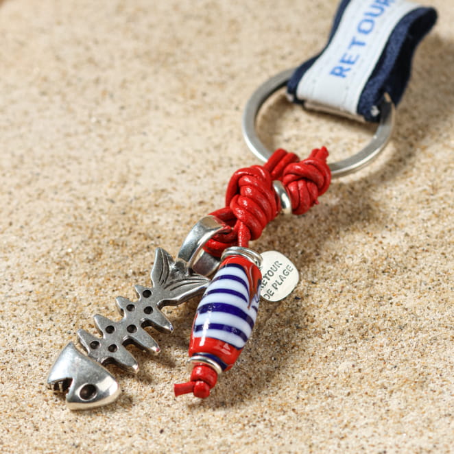 Porte-clés Maroni rouge, argenté et multicolore posé sur le sable – fabrication française